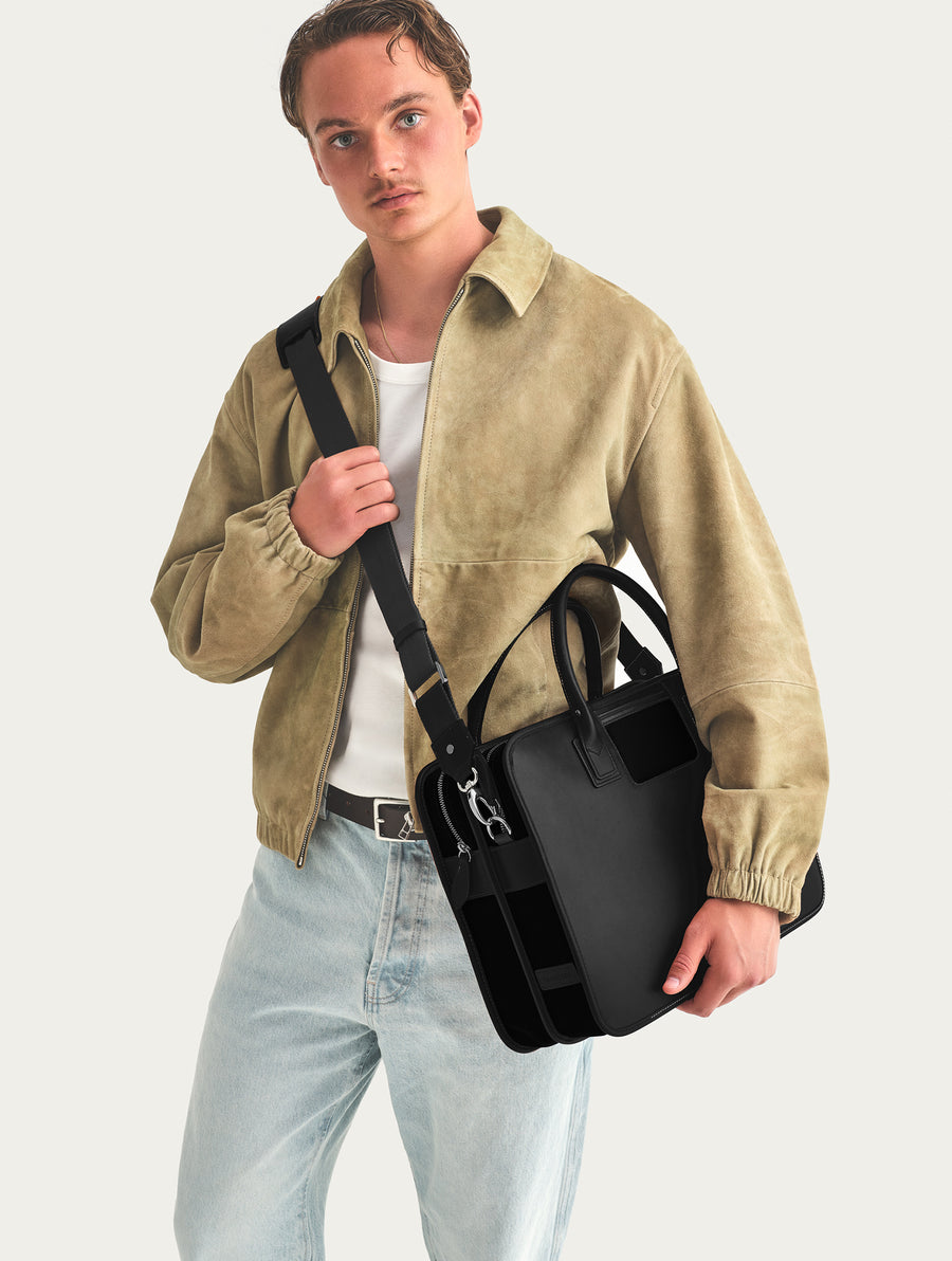 Man holding a black bag against a light gray background