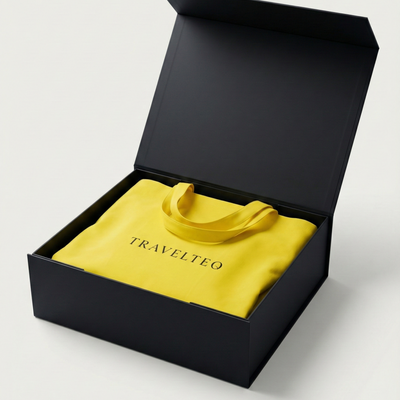 Yellow bag with 'TRAVELTEQ' branding inside an open black box on a light gray background