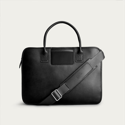 Black leather briefcase with a shoulder strap on a light gray background